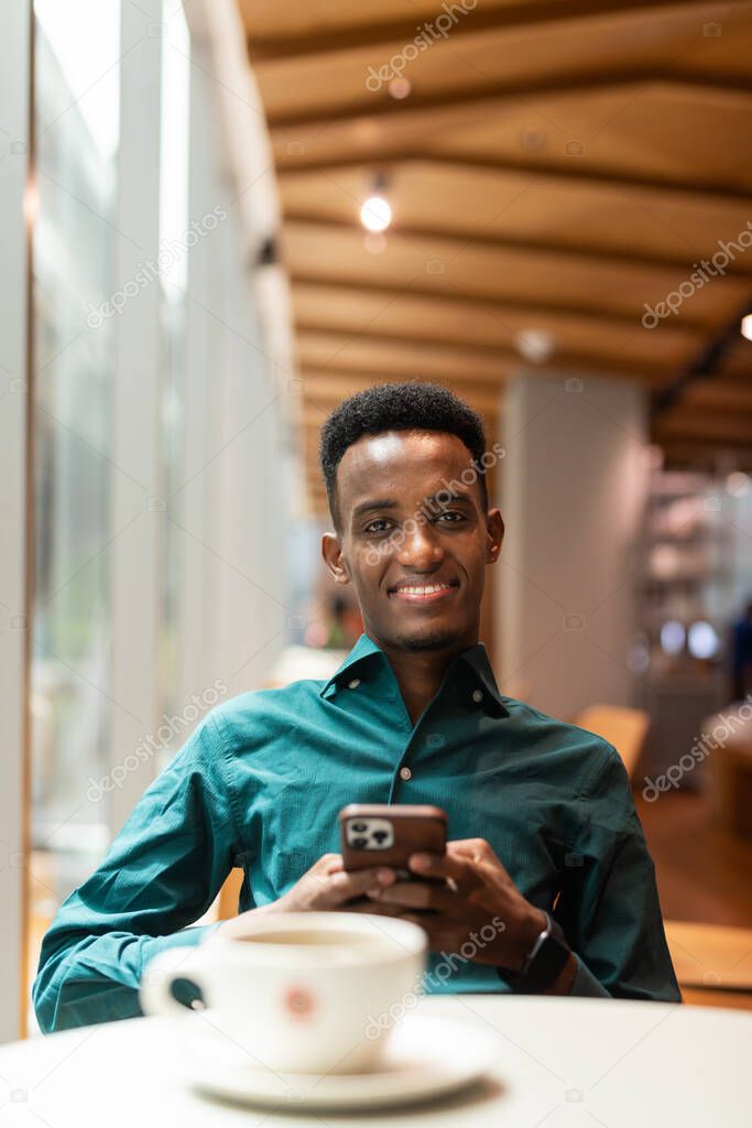 Portrait of handsome young black man in coffee shop