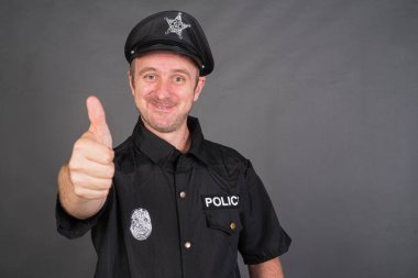 Polis üniforması giyen ve baş parmağını kaldıran mutlu beyaz adamın portresi.