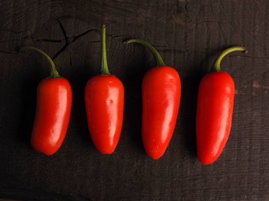Kırsal bir mutfak masasında taze yetişmiş dört acı biber, bahçıvanlık, organik gıda, yukarıdan manzara, sağlıklı beslenme konsepti.