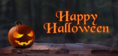 Cadılar bayramı balkabağı oyulmuş kabak Jack o fener rustik ahşap bir kalas üzerinde Mutlu Cadılar Bayramı, karanlık orman