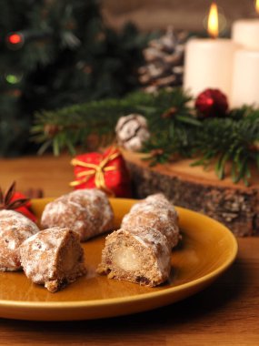 Lezzetli bir Noel çelengi, Noel süslemeleri ve mevsimlik yiyeceklerin önünde seramik bir tabakta çalınmış.