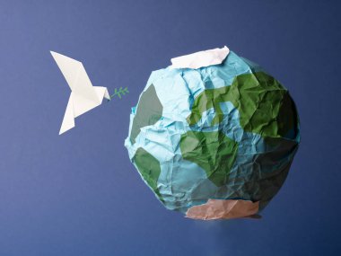 Origami barış güvercini, küresel özgürlük ve barış kavramına sahip buruşmuş kağıttan yapılmış soyut bir dünya.