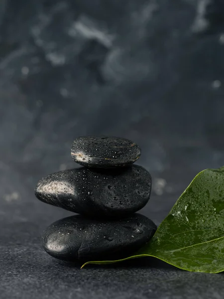 Gestapelte Massagesteine Mit Blättern Auf Einem Dunklen Steintisch Wellness Hintergrund — Stockfoto