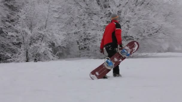 Tung klättring till toppen. snowboardåkare får upp kullen efter nedstigningen. — Stockvideo