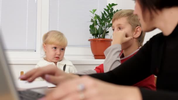 Mère célibataire. Deux jeunes enfants jouaient pendant que leur mère travaillait dur sur l'ordinateur portable. Zoom de mouvement . — Video