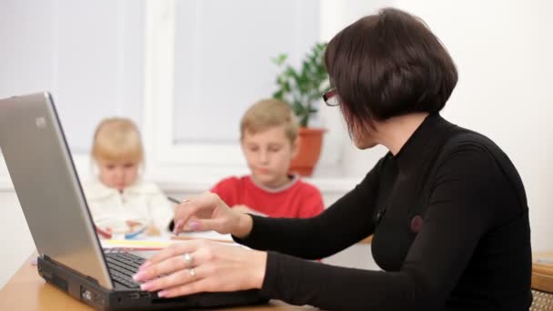 Madre single. Due bambini piccoli hanno giocato mentre la loro madre lavora duramente sul computer portatile. Zoom di movimento — Video Stock