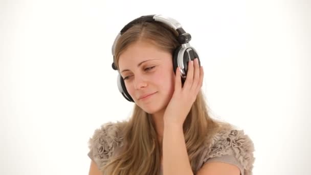 Muziek in de hoofdtelefoon. een meisje in een wit overhemd en hoofdtelefoon dansen op een witte achtergrond. twee frames. — Stockvideo