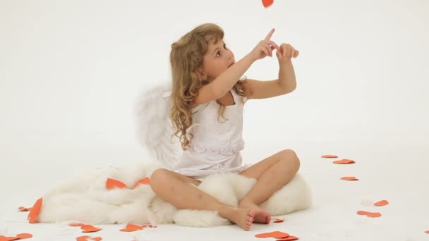 Маленька дівчинка одягнена як ангел в оточенні паперових сердець . — стокове відео