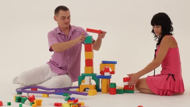 Dos adultos jugando con bloques de juguetes y tratando de construir un castillo . — Vídeos de Stock