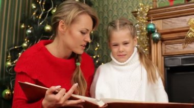 Anne kızına bir Noel ağacı altında bir hikaye okuma. bir hikaye okuma.