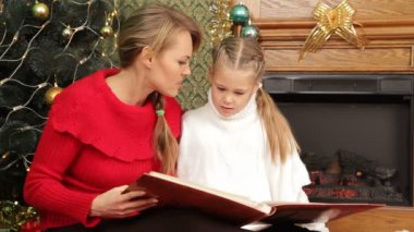 Anne kızına bir Noel ağacı altında bir hikaye okuma. bir hikaye okuma.