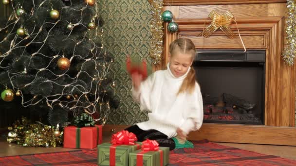 Chica mirando entre los regalos bajo un árbol de Navidad. Niño y regalos . — Vídeos de Stock