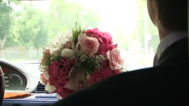Bruidegom met een boeket rijden in een auto — Stockvideo