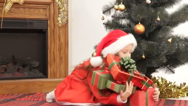 Flicka lägger julklappar under en julgran. — Stockvideo