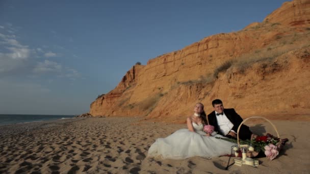 Los recién casados se relajan en la playa de arena . — Vídeo de stock