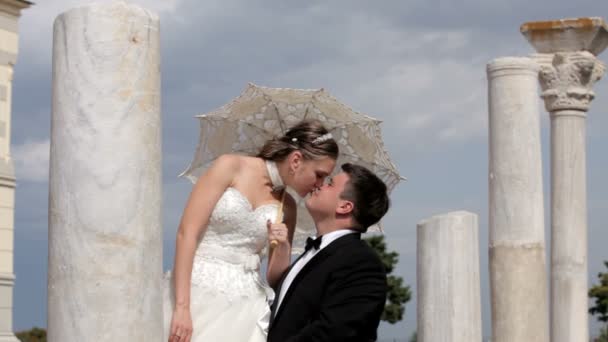 Bajo el paraguas un hombre besa a su esposa . — Vídeos de Stock