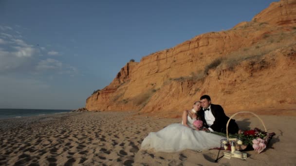 Los recién casados se relajan en la playa de arena . — Vídeo de stock