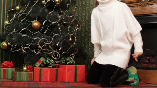 Niña eligiendo el mejor regalo bajo un árbol de Navidad. Muchos regalos. . — Vídeos de Stock