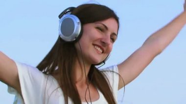 Kız büyük kulaklıklar. güzel kız, güzel mavi gökyüzünün büyük arka plan üzerinde kulaklık aracılığıyla müzik dinlemek.