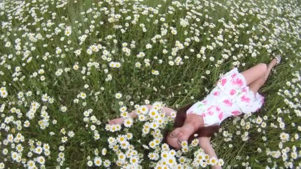 Chica en el campo de manzanilla. Una hermosa joven acostada en un hermoso campo de manzanilla . — Vídeos de Stock