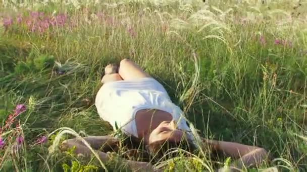Girl rolls on the field. Beautiful girl lying on the field. Then the rolls from the back to back. Moving camera. — Stock Video