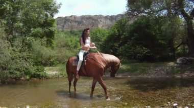 kadın at üstünde dar bir nehir geçiş.