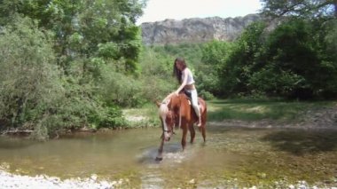 kadın at üstünde dar bir nehir geçiş.