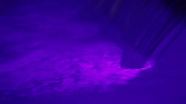 Cascada ligera violeta. Una pequeña cascada y un torrente de agua. Luz violeta agua . — Vídeos de Stock