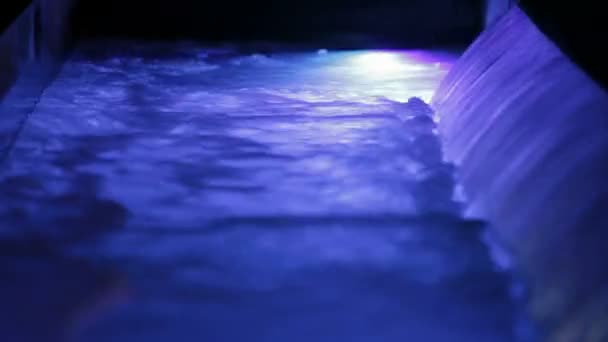 Violet licht waterval. een kleine waterval en een stortvloed van water. violet licht water. — Stockvideo