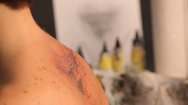 Een man schildert een tatoeage op de rug van een meisje. — Stockvideo