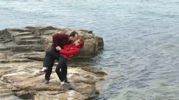 Couples have fun on the beach. In the second frame are sitting back to back. — Stock Video