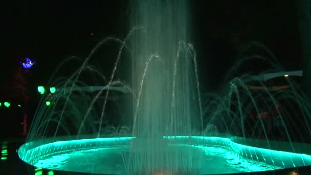 Fountains with colored lighting. Small and large fountains with multicolored highlighting the nature of the background. The background is blurred. Close-up. — Stock Video