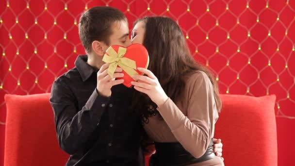 Par kyssas bakom hjärtformade presentförpackning — Stockvideo
