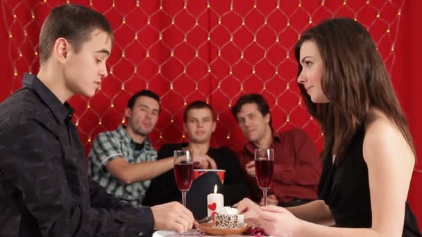 Cena. Pareja joven celebra el día de San Valentín para una cena romántica. Tres chicos mirándolos y comiendo palomitas de maíz — Vídeo de stock