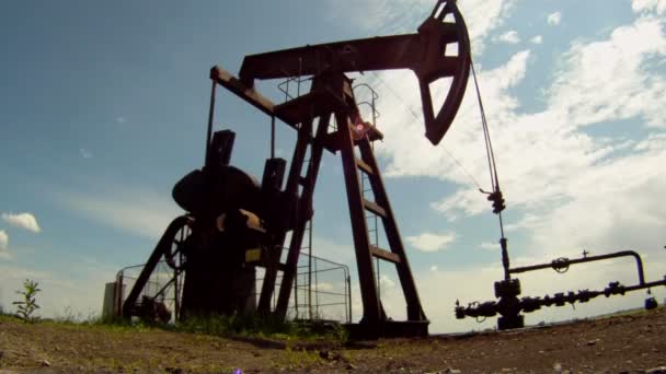 Producción de petróleo. La plataforma petrolera extrae recursos de la tierra. En el fondo un hermoso cielo azul . — Vídeo de stock