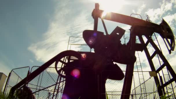 Producción de petróleo. La plataforma petrolera extrae recursos de la tierra. En el fondo un hermoso cielo azul . — Vídeos de Stock