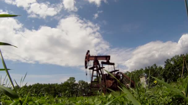 Produção de petróleo. A plataforma de petróleo extrai recursos da terra. No fundo um belo céu azul . — Vídeo de Stock