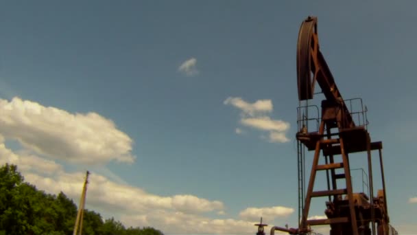 Produzione di olio. La piattaforma petrolifera estrae risorse dalla terra. Sullo sfondo un bel cielo blu . — Video Stock