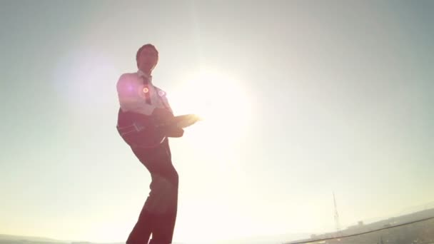 El hombre toca la guitarra en el fondo del sol — Vídeos de Stock