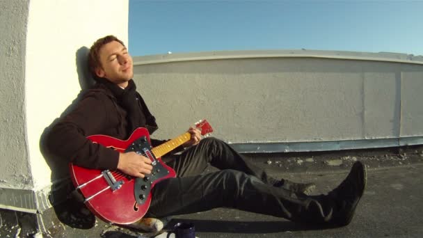 Un uomo seduto sul pavimento e suona la chitarra — Video Stock