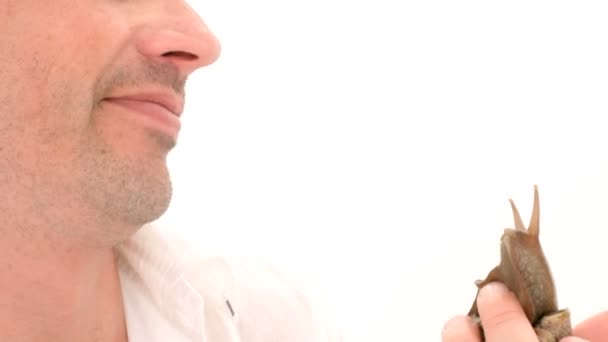 A man kisses a snail on a white background — Stock Video