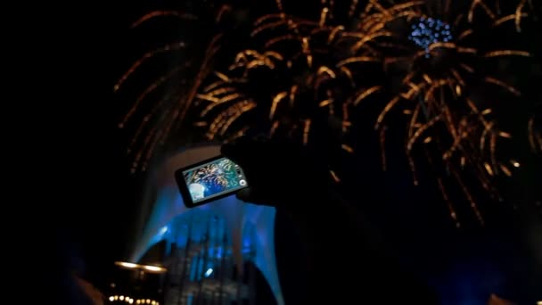 Hombre filmando fuegos artificiales festivos coloridos en la cámara . — Vídeo de stock