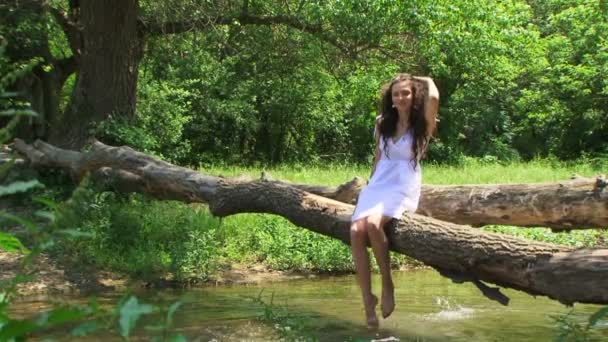 Curly brunette resting on a riverside. — Stock Video