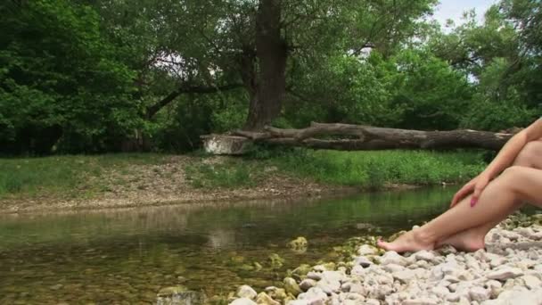 Woman sitting on a riverside. — Stock Video