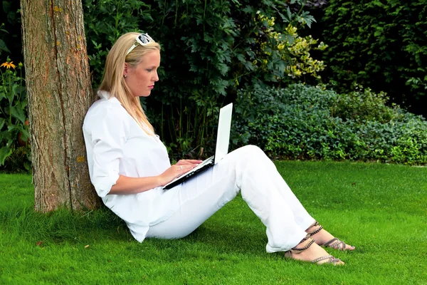 Vrouw met laptopcomputer in de tuin — Stockfoto