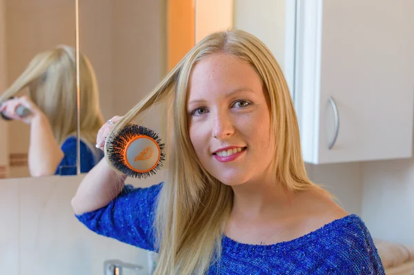 Vrouw die haar haar borstelt — Stockfoto