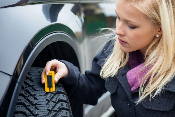 Vrouw maatregelen tire tread van een auto band — Stockfoto