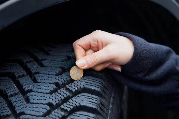 Женщина измеряет протектор шины автомобиля — стоковое фото