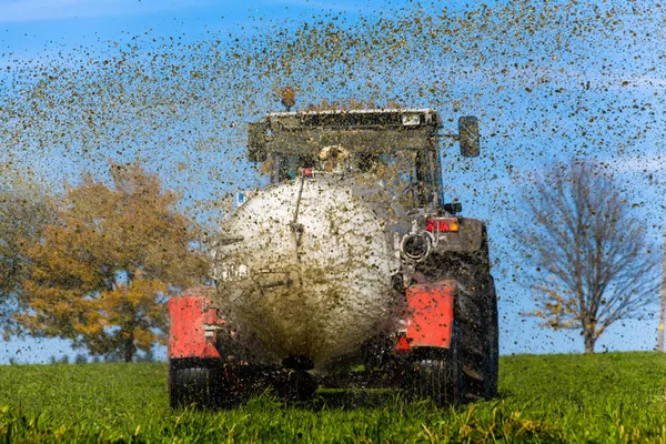 Traktor oplodní s hnojem pole — Stock fotografie