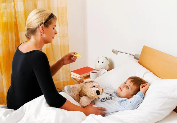 Mutter und krankes Kind im Bett. Grippe. — Stockfoto